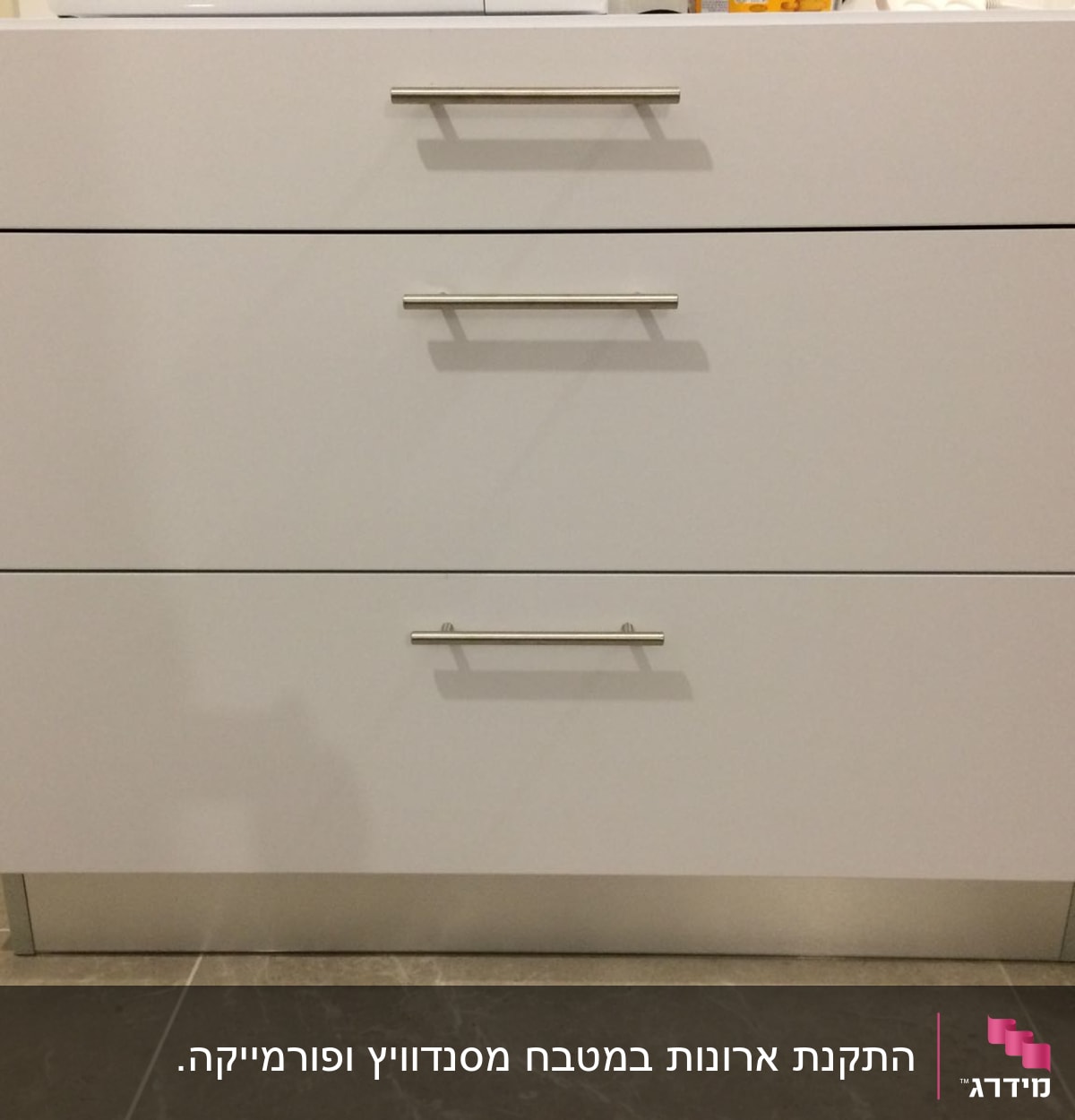 ארון מטבח לבן עם שלוש מגירות וידיות מתכת